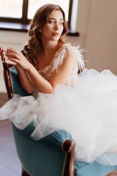 Bela noiva em vestido branco sentar na cadeira azul — Fotografia de Stock