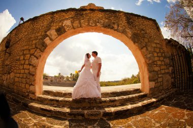 Beyaz elbiseli çift eski taş kemerin orada duruyor. balayı gezisi.