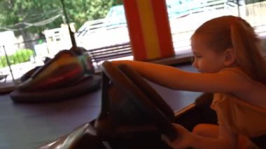 Kız lunaparkta araba sürüyor. Tatildeki çocuklar için eğlence.