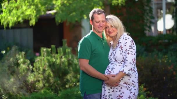 Gelukkig paar verwacht baby staan in de tuin in de achtertuin — Stockvideo