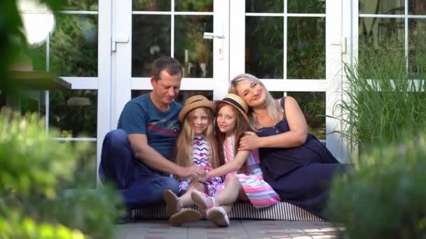 Família feliz em antecipação do bebê com duas filhas sentar-se no limiar — Vídeo de Stock