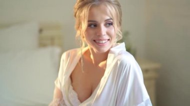 Yatağın üzerinde ipek bornozlu güzel sarışın gelin..