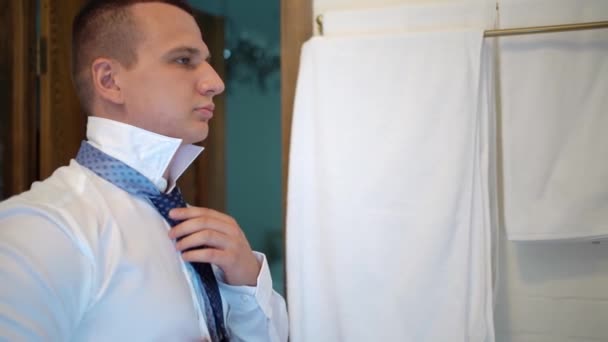 Man puts on tie and adjusts his shirt collar. going to work or wedding. — Stock Video