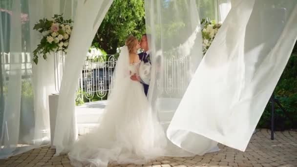 Recién casados de pie en rotonda con cortinas blancas que se desarrollan en el viento — Vídeos de Stock