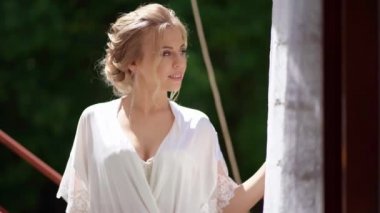 Açık havada duran ipek bornozlu güzel sarışın gelin. Düğünden önce sabah.