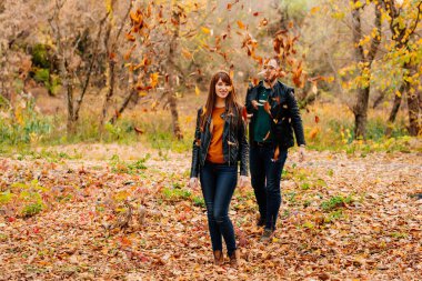 Erkekler sonbahar parkında kadınların üzerine kuru yapraklar yağdırır.. 