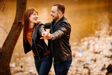 Erkek ve kadın nehir kenarındaki sonbahar parkında flört ediyorlar..