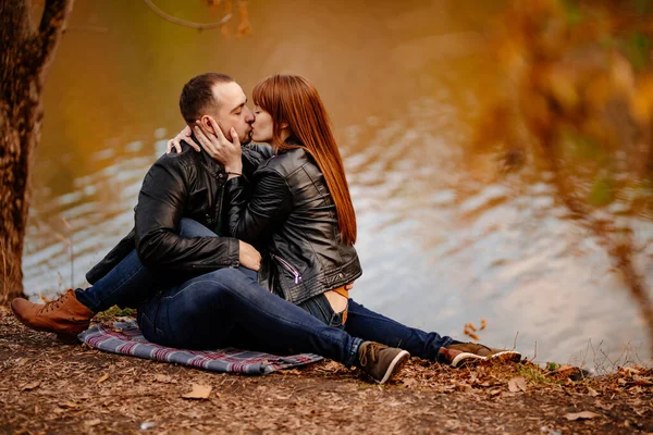 가을 공원의 강둑에 앉아 있는 부부. — 스톡 사진