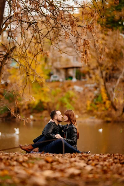 가을 공원의 강둑에 앉아 있는 부부. — 스톡 사진