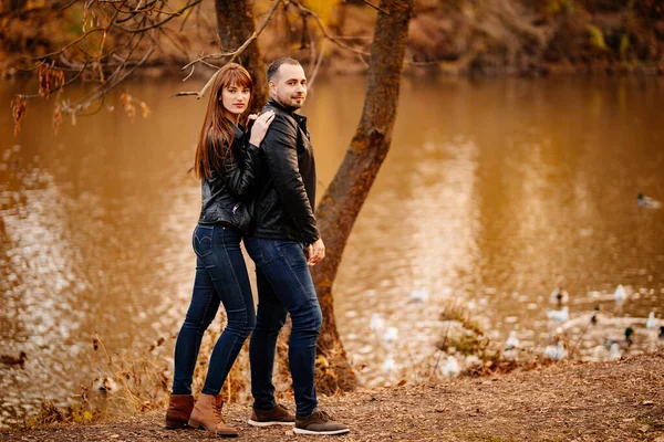 man and woman flirt in autumn park near river.