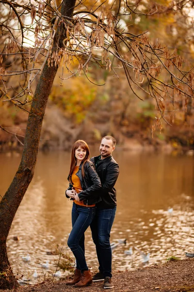 man and woman flirt in autumn park near river.