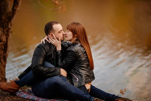 Casal sentado na margem do rio no parque de outono . — Fotografia de Stock