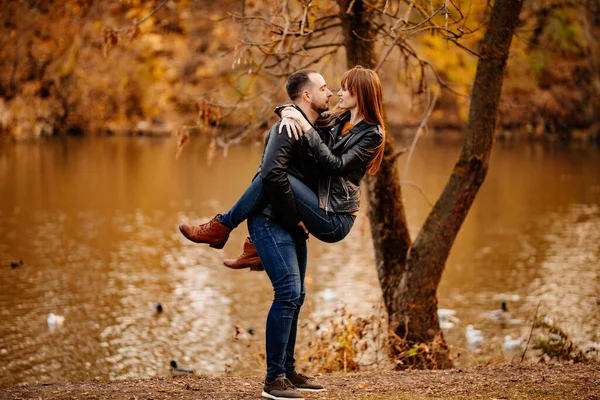 Uomo e donna flirtano nel parco autunnale vicino al fiume. — Foto Stock