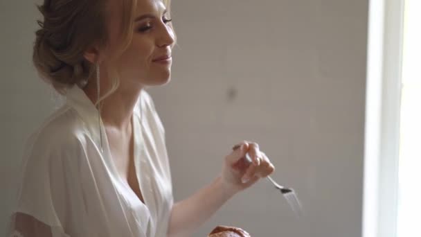 Woman eating cake with fork in bedroom and talks. morning before wedding. — Stock Video