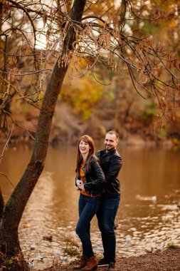 Erkek ve kadın nehir kenarındaki sonbahar parkında flört ediyorlar..