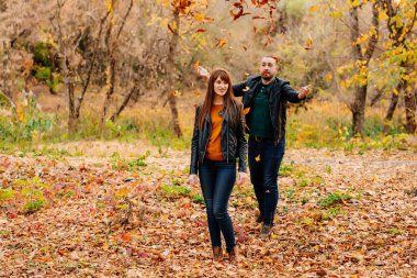 Erkekler sonbahar parkında kadınların üzerine kuru yapraklar yağdırır.. 