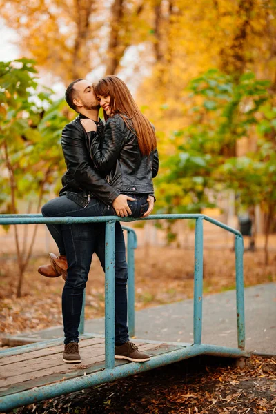 Man och kvinna på bro över bäcken i höstparken — Stockfoto