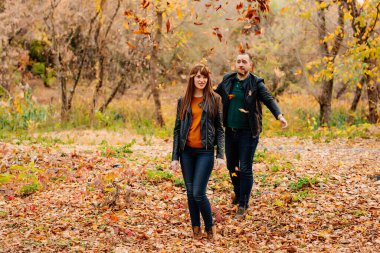 Erkekler sonbahar parkında kadınların üzerine kuru yapraklar yağdırır.. 