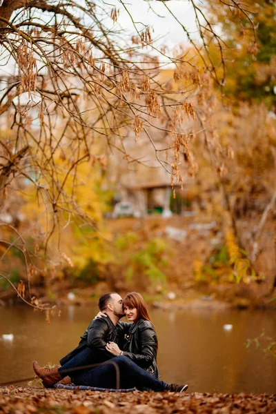 Coppia seduta sulla riva del fiume nel parco autunnale. — Foto Stock