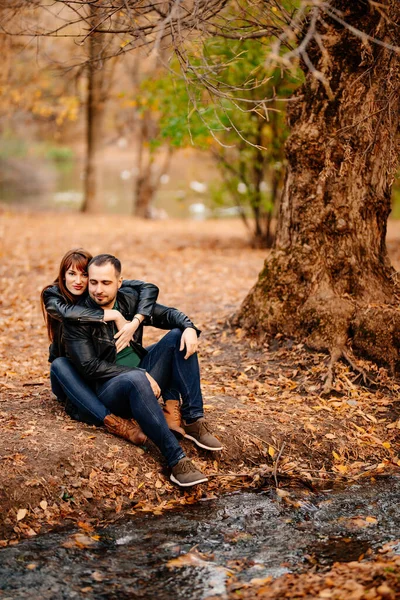 couple on bank of river in autumn park.