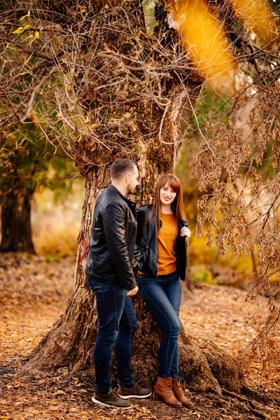 Sonbahar Parkı 'nda ağaçların yanında duran bir adam ve bir kadın..