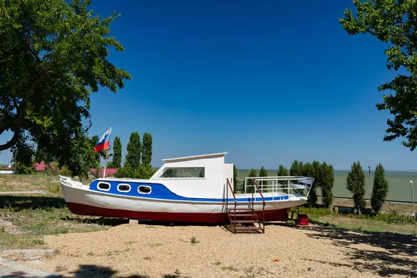 Old broken boat on beach painted in colors of Russian flag witha pennant. — Stock Photo, Image