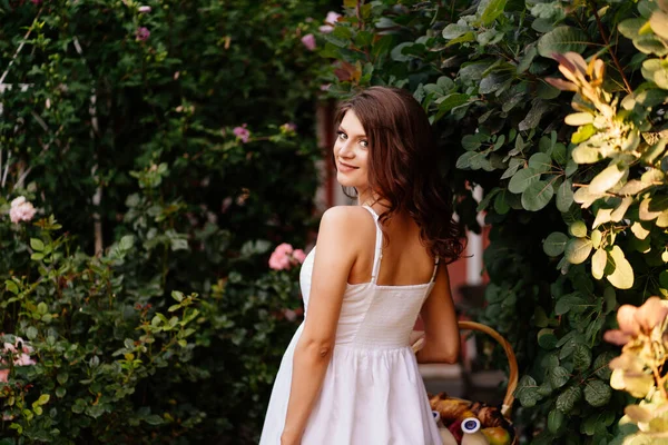 Schwangere im weißen Kleid mit Korbläufen im Park. — Stockfoto