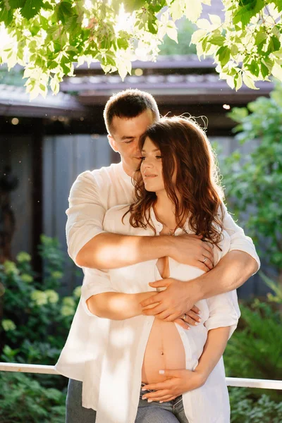 Adam nazikçe ve dikkatlice hamile kadını kucaklıyor.