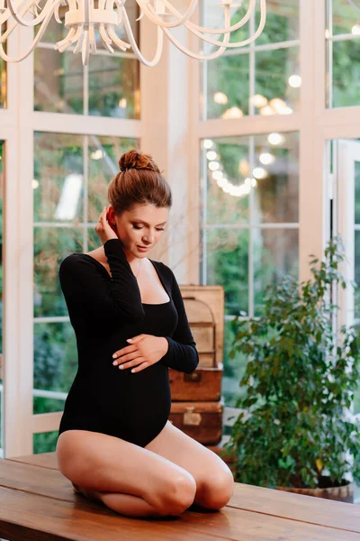 Enceinte en body noir s'assoit sur le sol en bois — Photo