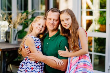 Babam evin bahçesinde iki tatlı kızı kucaklıyor..