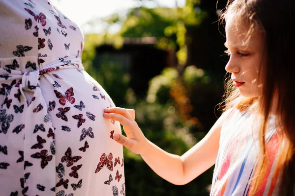 Dotter vidrör gravid mammas mage med fingrar — Stockfoto