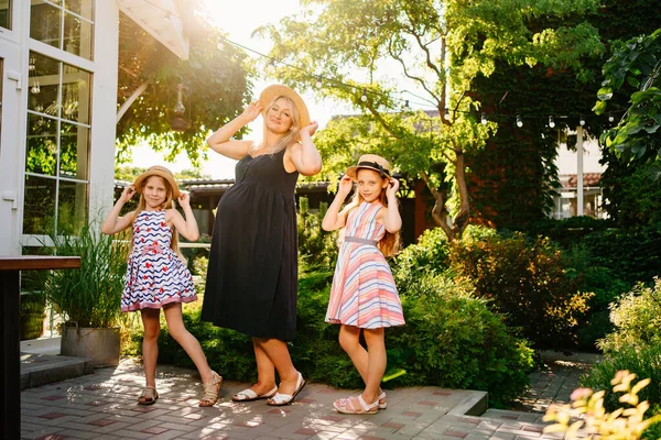 Embarazada de hijas en sombreros de paja al atardecer — Foto de Stock