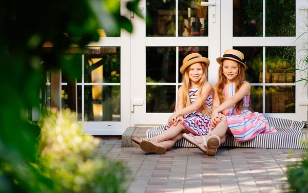 Сестры в соломенных шляпах на пороге у стеклянной двери — стоковое фото