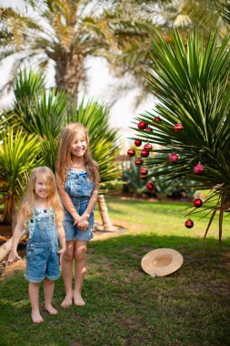 Palmiye ağacının yanındaki küçük kızlar Noel oyuncaklarıyla.