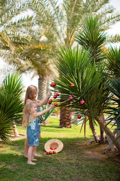 Дети девушки одеваются пальмы с рождественскими игрушками — стоковое фото