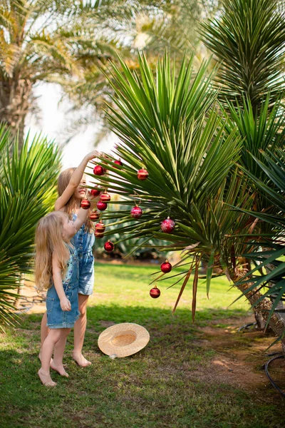 Дети девушки одеваются пальмы с рождественскими игрушками — стоковое фото