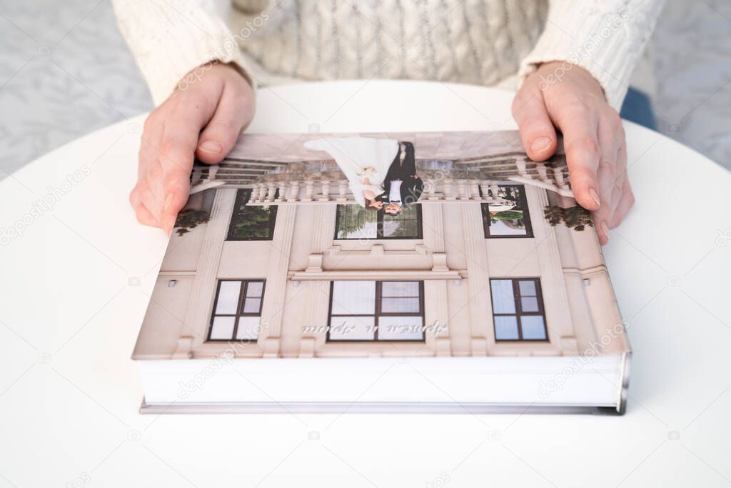 women's hands hold a wedding photo book