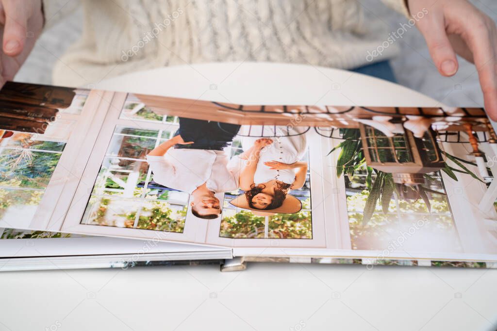 close up. woman flips through photo book from family pregnancy photo shoot.