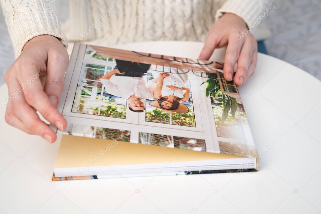 close up. woman flips through photo book from family pregnancy photo shoot.