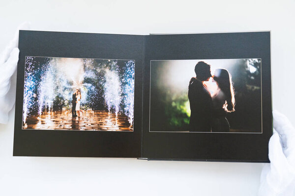 hands in white gloves flipping through a photo book with wedding photos. 