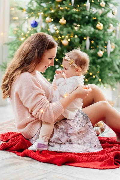Μητέρα και κόρη κάθονται στο χριστουγεννιάτικο δέντρο. — Φωτογραφία Αρχείου