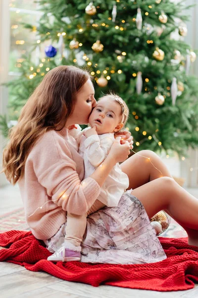 Madre e hija sentadas en el árbol de Navidad. — Foto de Stock