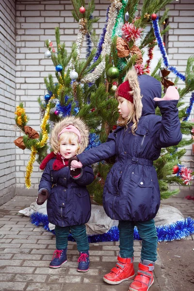 Meninas engraçadas ficar na rua perto da árvore de Natal. — Fotografia de Stock