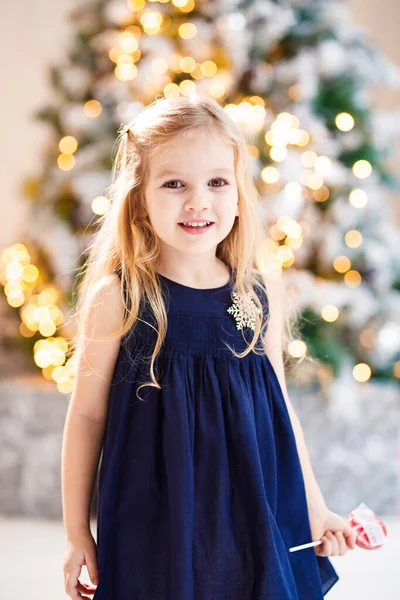在圣诞树附近拿棒棒糖的小女孩 — 图库照片