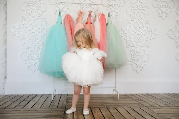 Dítě dívka v šatech v blízkosti ramínko se slavnostním oblečení — Stock fotografie