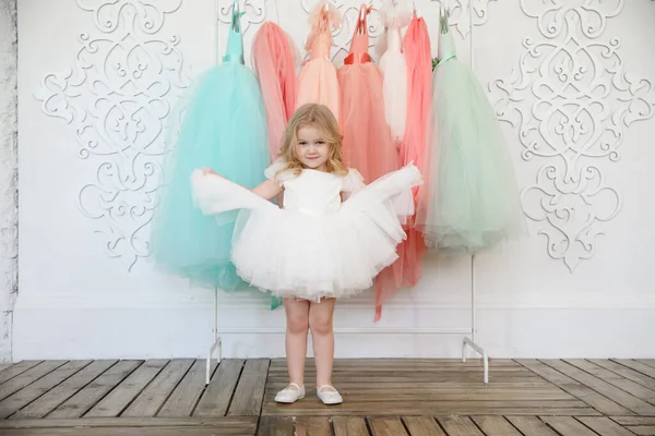 Дівчинка в сукні біля вішалки зі святковим одягом — стокове фото