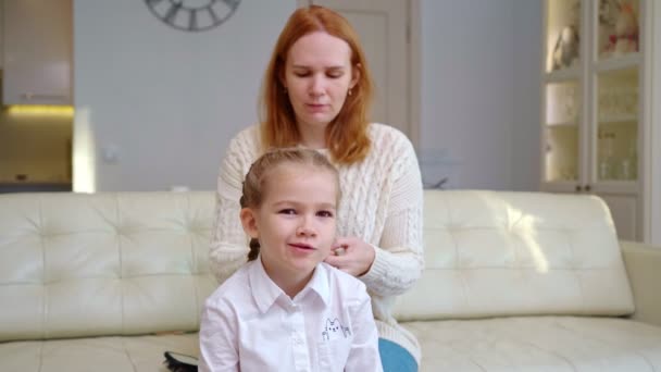 Mammas händer fläta hennes söta dotters flätor till skolan på morgonen. — Stockvideo