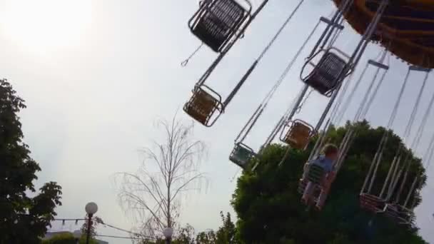Карусель цепи вращается в парке аттракционов. девушки катаются на качелях в выходные — стоковое видео