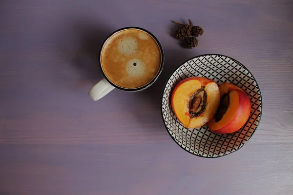 a up of coffee and nectarine on a wooden lavender background. best breakfast
