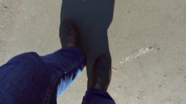 Bir adam bir asfalt yolda yürür. Kot pantolon ve karanlık çizmeler üstten görünüm bacaklar. Yaz güneşli gün ve bacaklar uzun bir gölge.